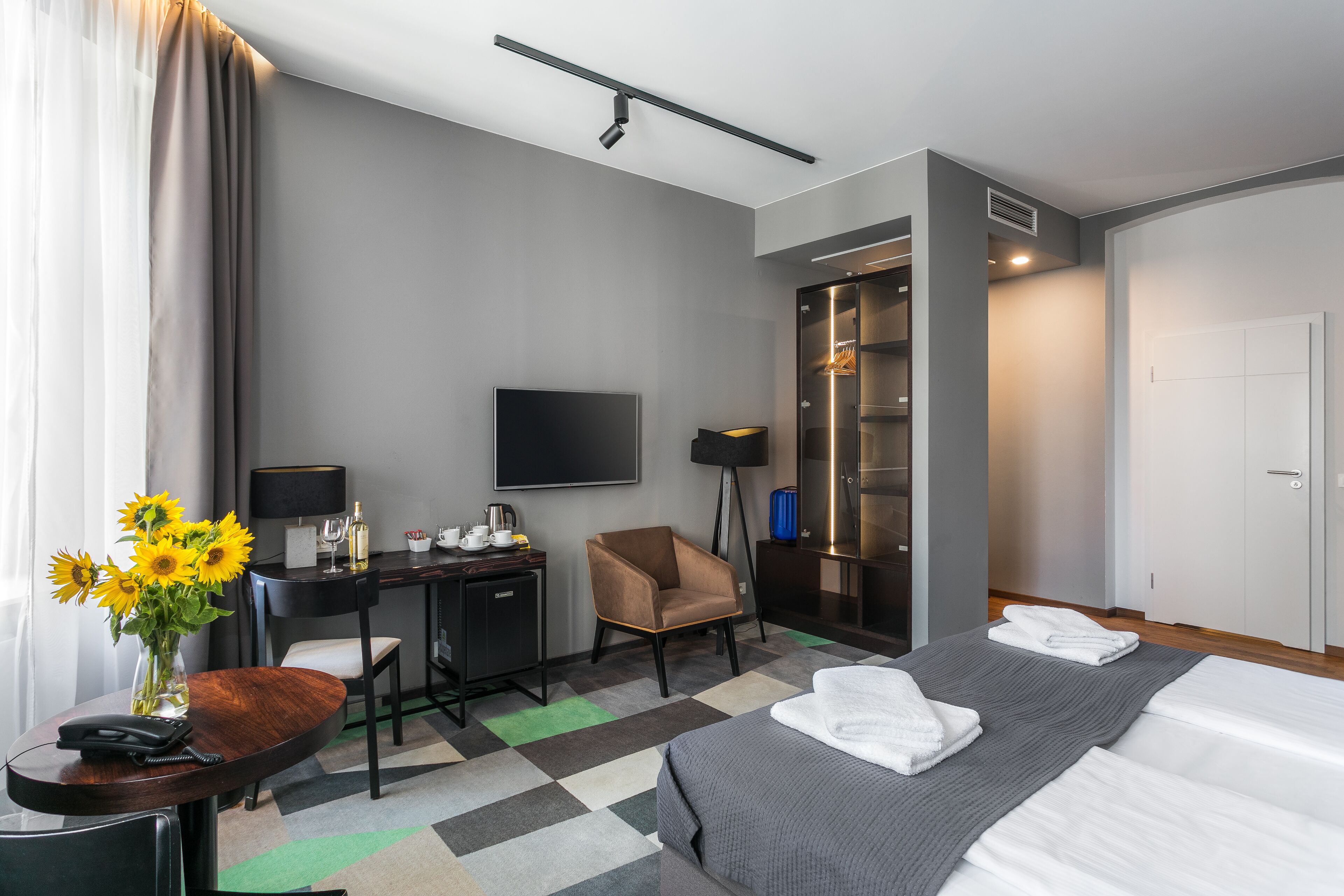 Een hotelkamer met een bed, een bureau, een stoel, een televisie en een kast.