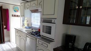 Una cucina con mobili bianchi, un fornello, un forno a microonde e una macchina per il caffè.