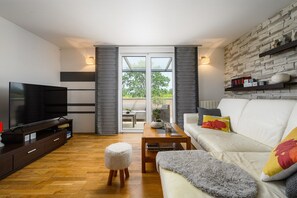 A modern living room with a flat-screen TV, a sofa, a coffee table, and a small ottoman. - Premium Apartment David (Dracevac)
