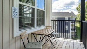 A covered outdoor area with a wooden table and chairs, a 'No Smoking' sign, and a view of a house in the background.