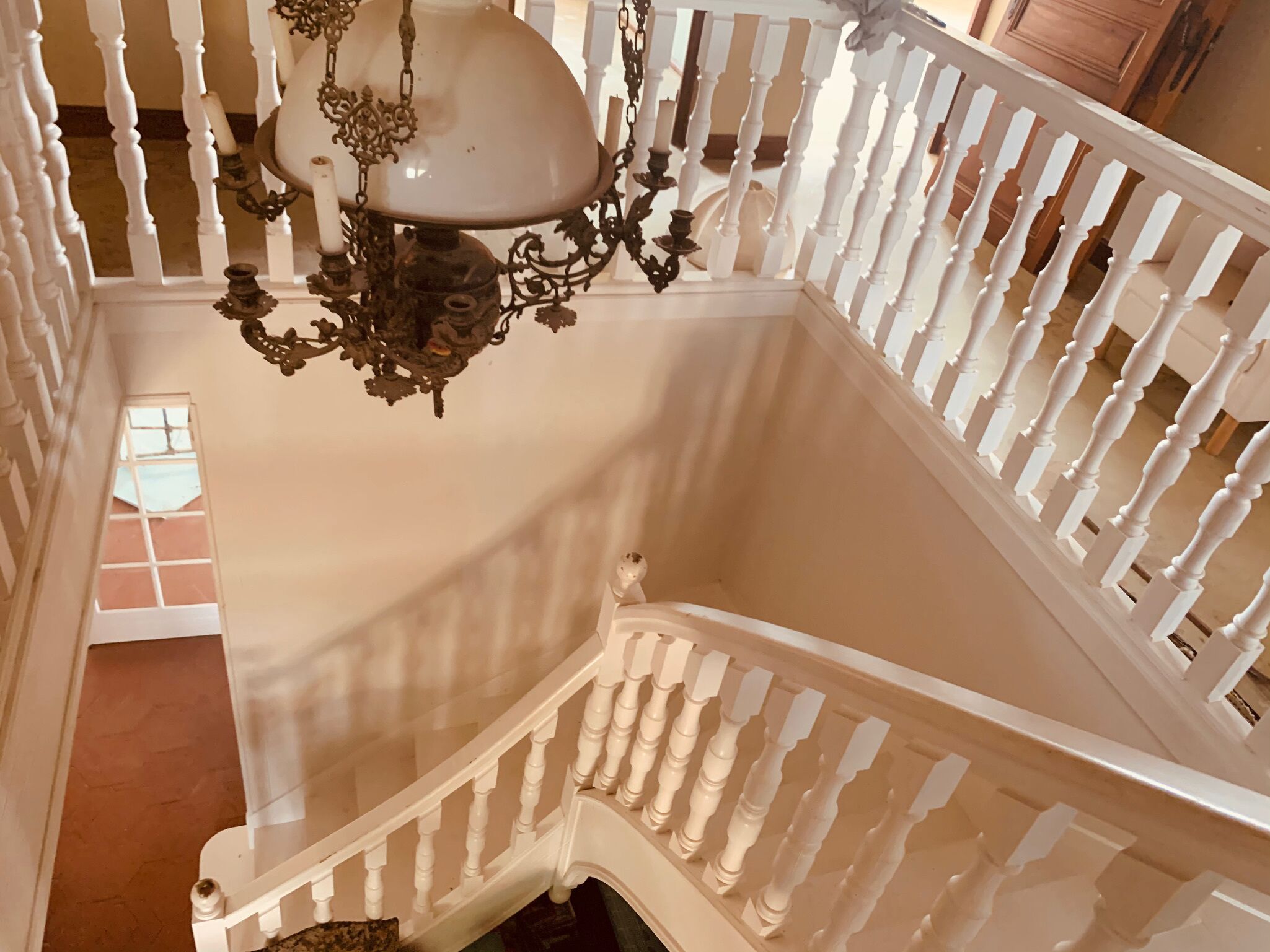 Una majestuosa escalera con barandillas blancas y un candelabro decorativo.