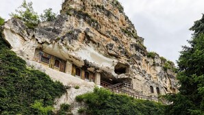 A cave-like structure with a staircase leading up to a small building with arched windows. - Anna Palace Hotel (Ruse)