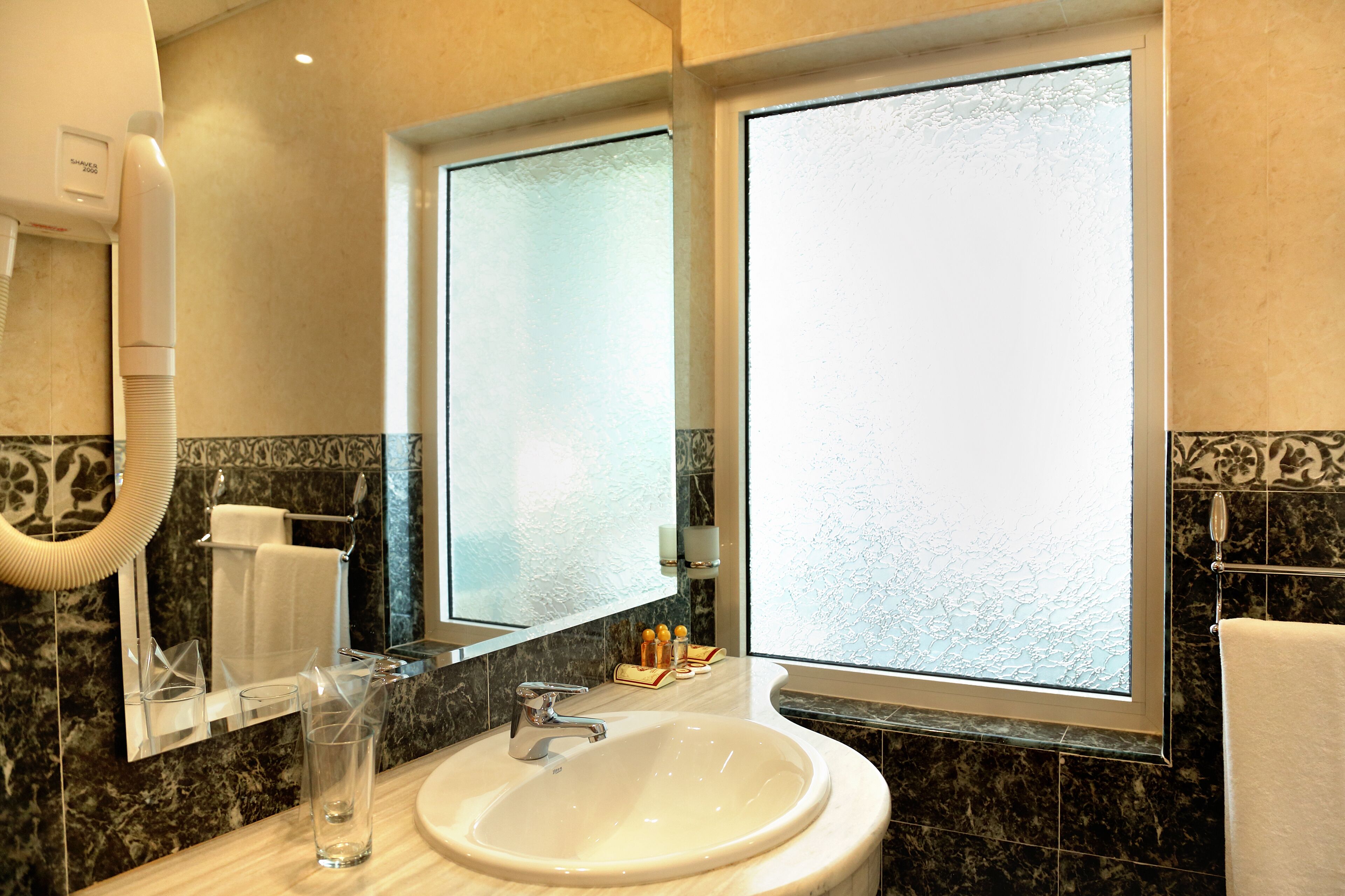 A bathroom with a large mirror, a sink, and a hairdryer.