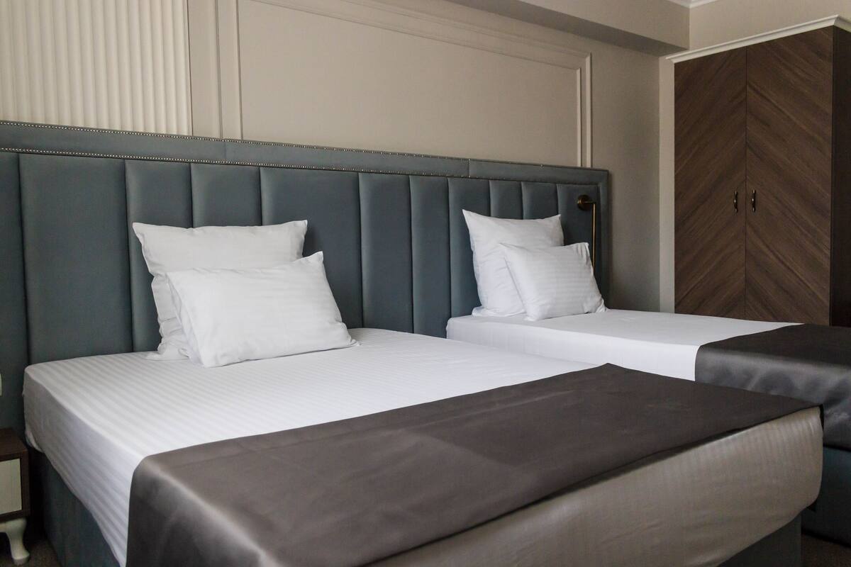 A hotel room with two beds, a large wardrobe, and a nightstand.