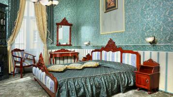 A bedroom with a four-poster bed, a wooden nightstand, a dresser, a chair, and a mirror.