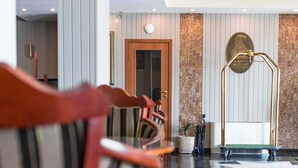 A hotel lobby with striped chairs, a reception desk, and a decorative wall with vertical lines. - Anna Palace Hotel (Ruse)