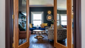 A spacious living room with a wooden floor, a blue sofa, a grey armchair, and a coffee table. - Luxury Beachfront Penthouse, Panoramic Sea Views (Herne Bay)