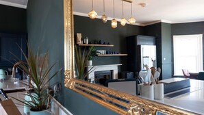 A modern living room with a large mirror, a fireplace, and a dining area. - Luxury Beachfront Penthouse, Panoramic Sea Views (Herne Bay)