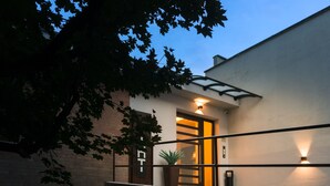 Un bâtiment moderne avec une entrée dotée d’une porte en verre, un pot de fleurs et un mur en briques.