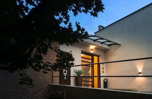 Un edificio moderno con puerta de acceso de vidrio, una planta en maceta y un muro de ladrillo.