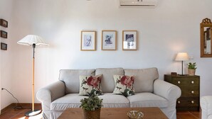 Ein Wohnzimmer mit einer Couch, einem Couchtisch, einer Stehlampe, einem Beistelltisch mit einer Lampe und gerahmten Bildern an der Wand.