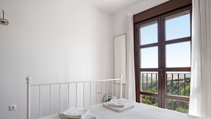 Una camera da letto con un letto bianco, una finestra vista e un termosifone bianco.