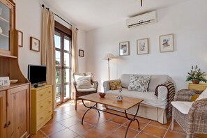 A living room with a sofa, chairs, a coffee table, a TV, and a cabinet.