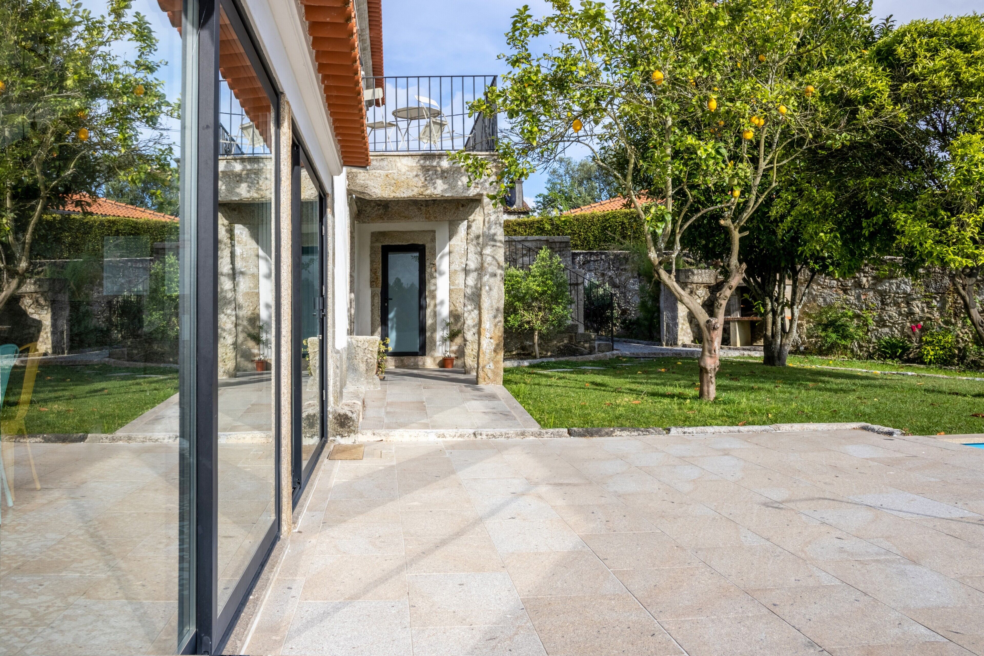 A modern house with a glass door entrance, a stone pathway, and a well-maintained garden.