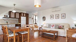 A kitchen with a microwave, refrigerator, and dining table with chairs. - Apartment ‘Cobijadas75 Corredera’ with Mountain View & Wi-Fi (Vejer de la Frontera)