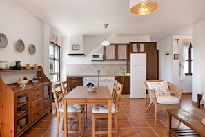 A kitchen with a dining table, chairs, a washing machine, and a refrigerator.