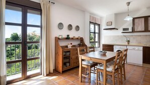 A kitchen with a dining table, chairs, a microwave, and a view through the window. - Apartment ‘Cobijadas75 Corredera’ with Mountain View & Wi-Fi (Vejer de la Frontera)