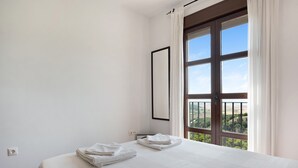 A bedroom with a large window, a bed with white linens, and a view of greenery outside. - Apartment ‘Cobijadas75 Corredera’ with Mountain View & Wi-Fi (Vejer de la Frontera)