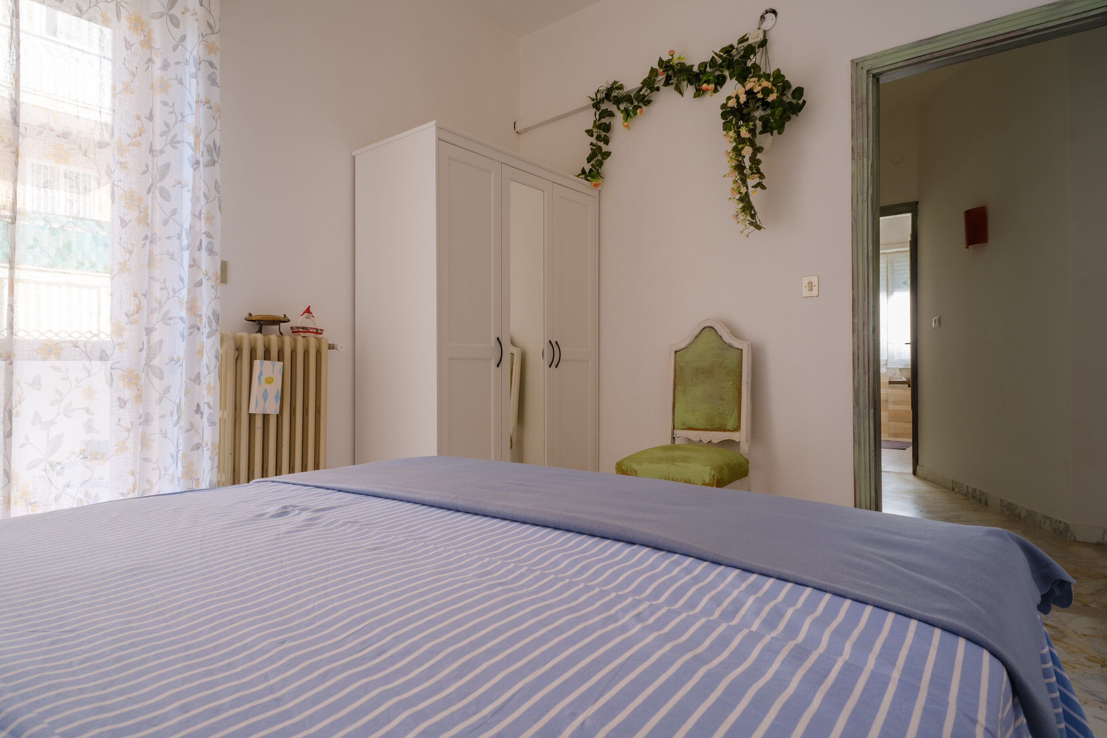 Un dormitorio con cama, armario, radiador y espejo.
