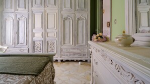 Une pièce avec une grande armoire blanche, une commode agrémentée d’objets décoratifs et un tapis à motifs sur le sol.