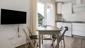 Una cucina moderna con un tavolo da pranzo, sedie, una lavatrice e un televisore montato a parete.