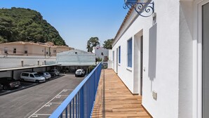 Ein Balkon mit Blick auf einen Parkplatz und ein Gebäude mit weißer Fassade und blauen Akzenten.