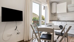 Eine moderne Küche mit integriertem Waschmaschinenanschluss, einer Essecke mit Tisch und Stühlen sowie einem großen Fenster mit Vorhängen.