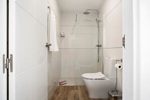 A modern bathroom with a glass shower enclosure, a white toilet, and a wooden floor.