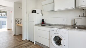 A modern kitchen with white appliances, a washing machine, and a countertop with a sink. - Apartment 'Casa de 10 - 5A' with Mountain View, Shared Pool & Wi-Fi (Vejer)