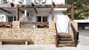 A stone wall with a wooden bench and steps leading to a building entrance.