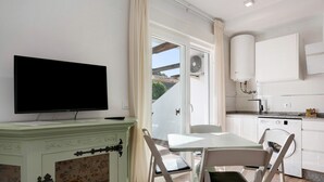A modern kitchen with white cabinets, a built-in washing machine, and a dining area with a table and chairs.