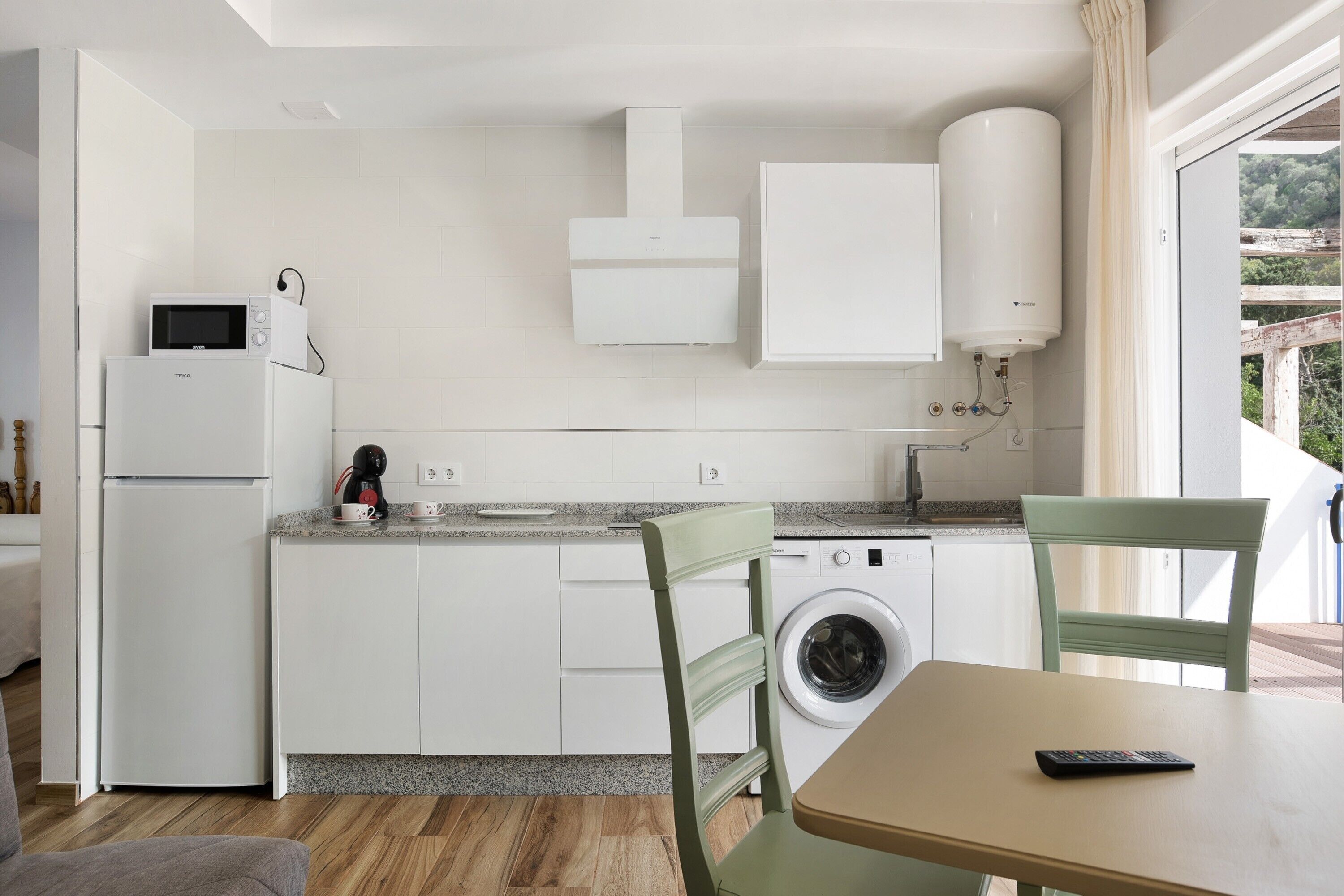 A compact kitchen with a washing machine, a microwave, and a coffee maker.