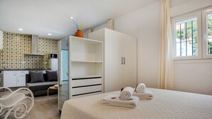Un dormitorio con cama, armario, sofá, una mesita y una silla.