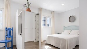 A bedroom with a bed, a chair, a wardrobe, a window, and a potted plant.