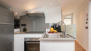 A modern kitchen with a built-in oven, stainless steel appliances, and a glass backsplash. - Seaview Modern Loft - Seaview Modern Loft (Zakynthos)