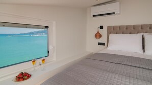 A bedroom with a bed, a window with a view of the sea, and a small table with drinks and fruit. - Seaview Modern Loft - Seaview Modern Loft (Zakynthos)
