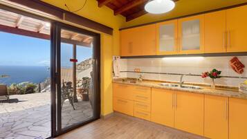 A kitchen with yellow cabinets, a stainless steel sink, and a view through the glass door.