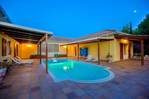 A swimming pool with a pergola and lounge chairs, surrounded by a tiled patio area. - Hacienda Olivo - Hacienda Olivo (Zakynthos)