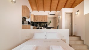 A bedroom with a large bed, a wooden ceiling, and a view of a kitchen and dining area. - Spartia Suites - Brand New Seaview Suites - Spartia Suites - Brand New Seaview Suites (Zakynthos)