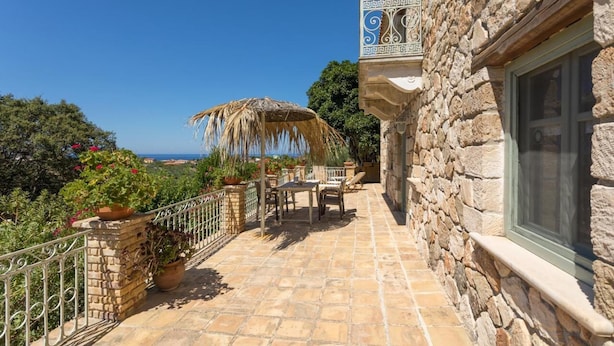 A stone building with a balcony overlooking a scenic view.