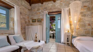 A rustic stone room with a bed, a sofa, and a table.