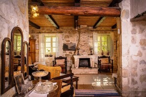 Une pièce rustique aux murs de pierre, avec des poutres en bois, une cheminée et des meubles anciens.