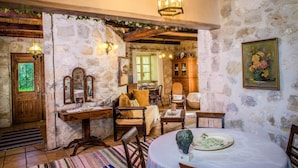 Una stanza rustica con pareti in pietra, mobili in legno e un tavolo da pranzo con un piatto verde.