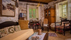 Una stanza rustica con un divano di legno, un tavolo da pranzo con sedie, un armadietto in legno e una finestra con tende.