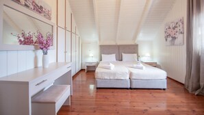 A bedroom with two beds, wooden flooring, a white wardrobe, and a bench. - Zante Sun I - Getaway Villa - Zante Sun I - Getaway Villa (Zakynthos)