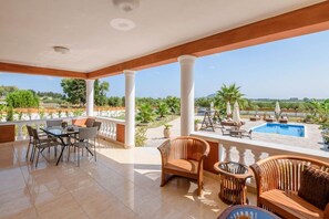 A covered outdoor area with a pool, seating, and a view of greenery. - Zante Sun II - Getaway Villa - Zante Sun II - Getaway Villa (Zakynthos)