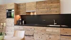 Eine moderne Küche mit Holzschränken, einer schwarzen Arbeitsplatte und einem Edelstahl-Spülbecken.