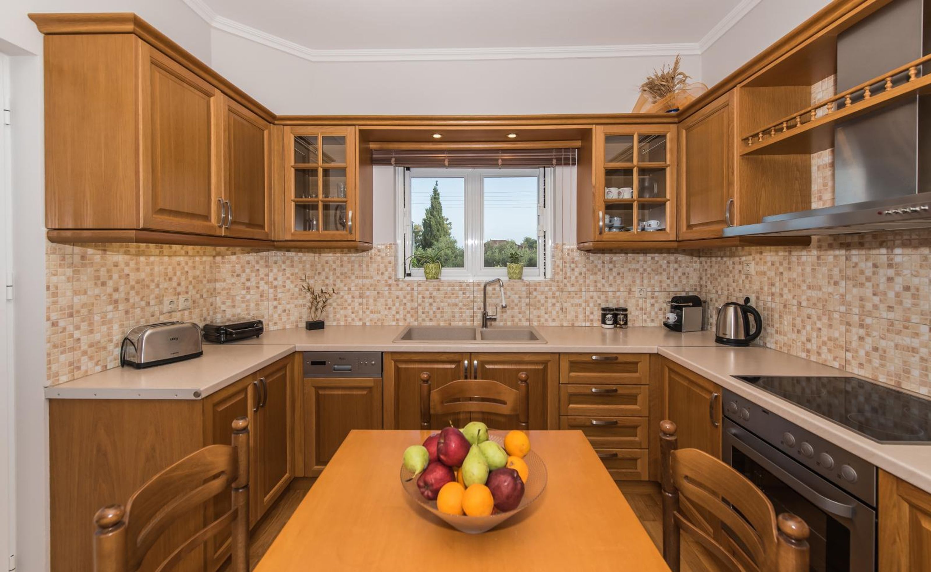 Una cocina con armarios de madera, una ventana con plantas, un lavamanos y una estufa.