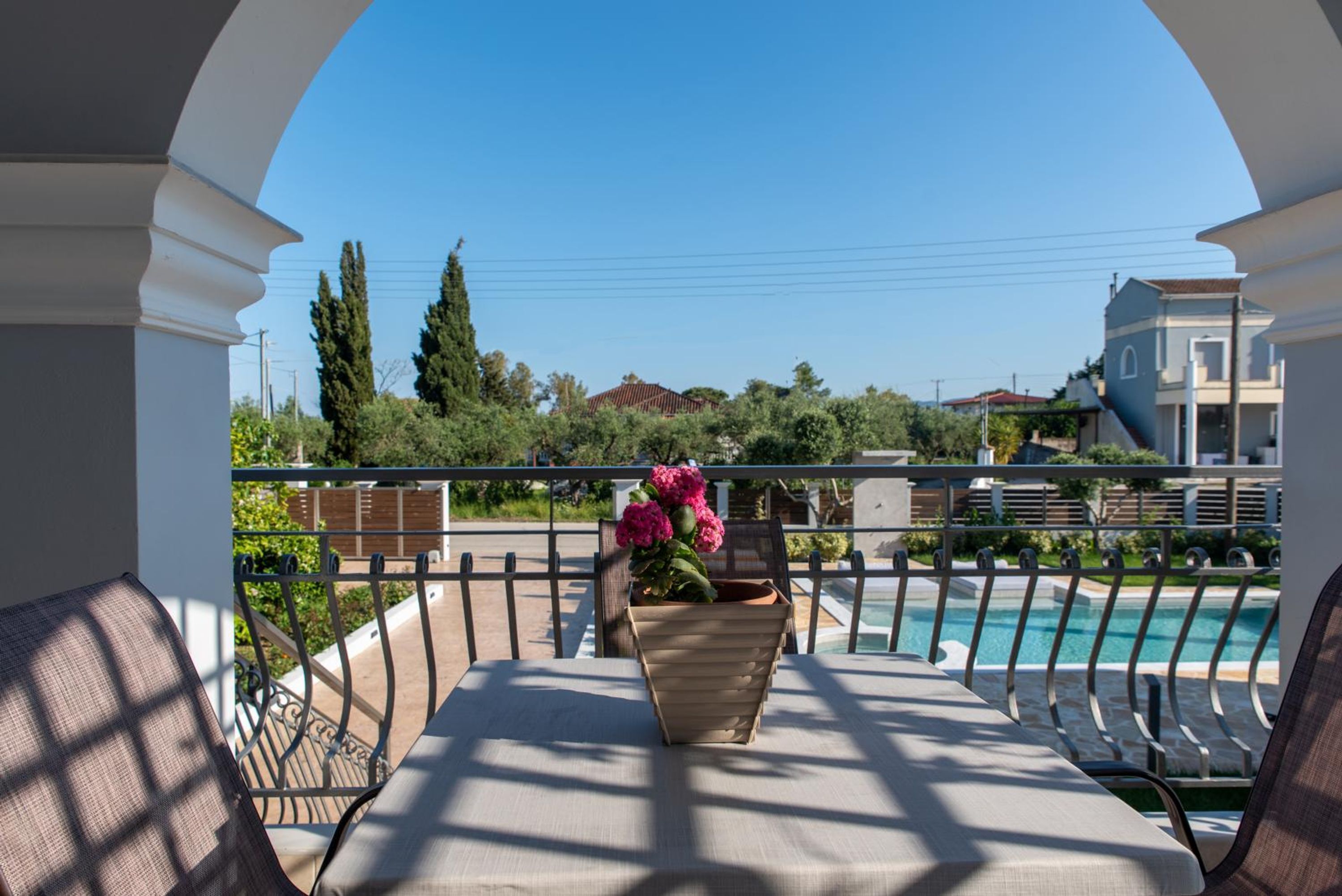 Ein Balkon mit Blick auf einen Swimmingpool, einer Topfpflanze und einem strahlend blauen Himmel.