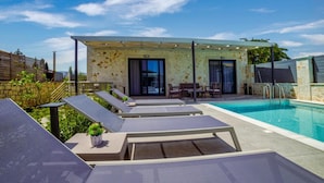 A modern outdoor pool area with lounge chairs and a covered seating area.